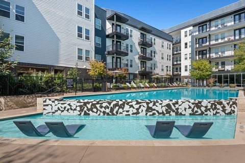 an apartment pool with an apartment building in the background